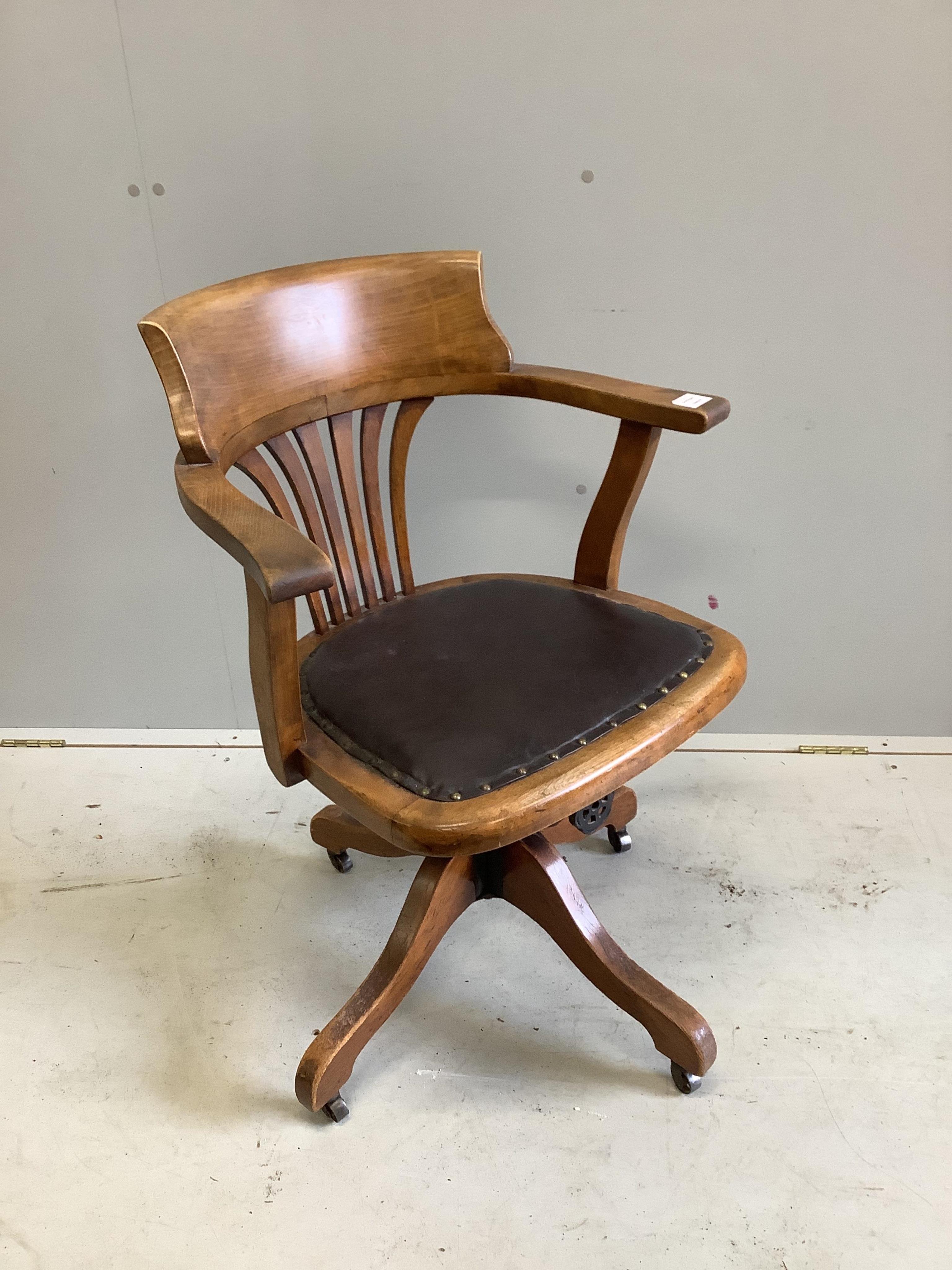 An Edwardian stained beech revolving desk chair, width 62cm. Condition - faded, otherwise good